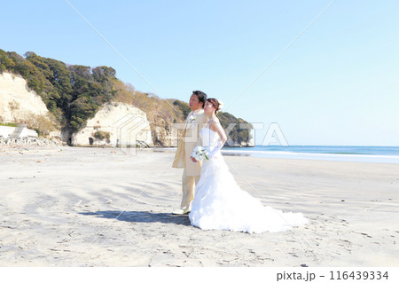 ウエディングドレス姿の新婦様とタキシード姿の新郎様フォトウエディング青空の美しい海ロケーション撮影 116439334