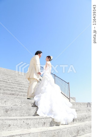 ウエディングドレス姿の新婦様とタキシード姿の新郎様フォトウエディング青空の美しい海ロケーション撮影 116439343