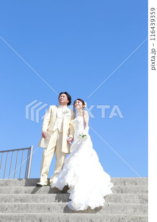 ウエディングドレス姿の新婦様とタキシード姿の新郎様フォトウエディング青空の美しい海ロケーション撮影 116439359