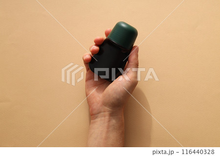 Cosmetic jar in hand on beige background, top view 116440328