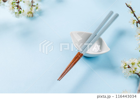 Table adorned with cherry blossom branch and chopsticks, epitomizing Japanese food culture 116443034
