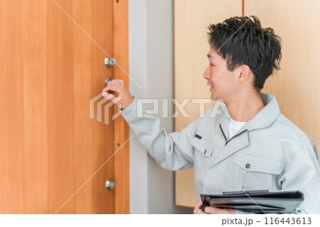 玄関ドアをチェックする工務店・ハウスメーカーの作業員の男性 116443613