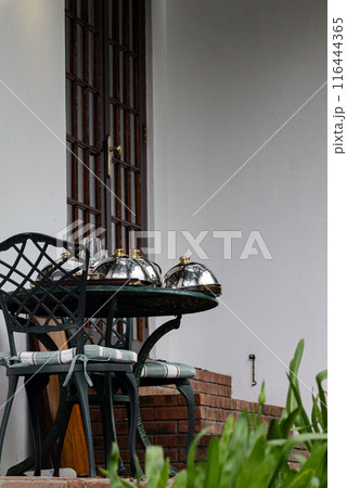 Breakfast on the terrace near the hotel room. plates covered with metal lids for hot dishes on table Breakfast on the terrace near the hotel room. plates covered with metal lids for hot dishes on table 116444365