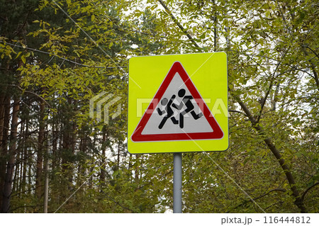 Road sign, installed near schools. Be careful, children. Yellow square, with a red triangle, white, with the image of running people Road sign, installed near schools. Be careful, children. Yellow square, with a red triangle, white, with the image of running people 116444812