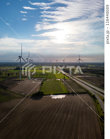 Relish the scenic wind farm vista amidst green fields and under a clear blue sky Relish the scenic wind farm vista amidst green fields and under a clear blue sky 116448089