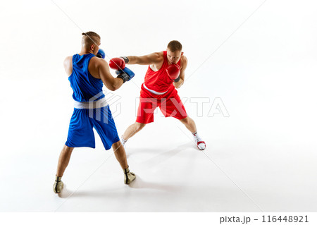 Dynamic scene of two athletes, one in red and one in blue, training their fighting techniques against white studio background. 116448921