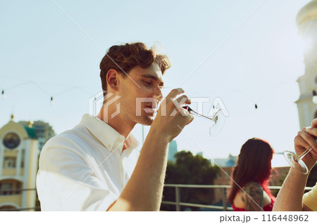 Warmth of sun and joy of friendship combine as friends raise their glasses in toast. Party outdoor. 116448962