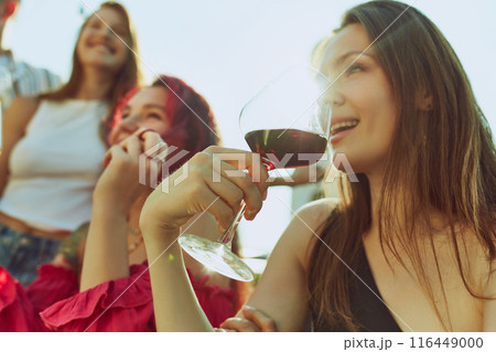 Portrait of festive toast among friends, men and women, their drinks glistening in warm rays of sun. Hot summer holidays. Portrait of festive toast among friends, men and women, their drinks glistening in warm rays of sun. Hot summer holidays. 116449000