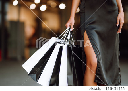Shopping bags in the hands. Fashion woman with packages after shopping. Black friday, sale. Shopping bags in the hands. Fashion woman with packages after shopping. Black friday, sale. 116451333