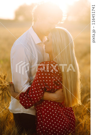 Young happy couple hugging on a wheat field, on the sunset. Enjoying time together. 116451741