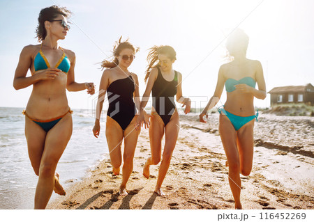 Four young girls having fun on the beach. Group of girlfriends enjoying on beach holiday. Summer lifestyle. 116452269