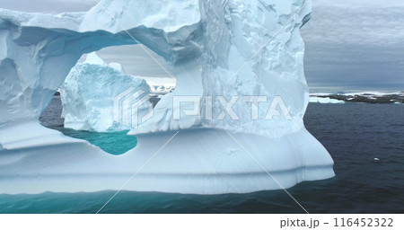 Polar climate change melting icebergs in Antarctica. Huge hole cave arch window melted ice wall drifting Antarctic ocean close up. Arctic winter landscape, global warming problem. Drone shot zoom in Polar climate change melting icebergs in Antarctica. Huge hole cave arch window melted ice wall drifting Antarctic ocean close up. Arctic winter landscape, global warming problem. Drone shot zoom in 116452322