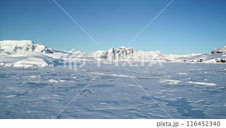 Aerial fly over winter mountain landscape in Antarctica. Polar frozen ocean landscape covered by snow under blue sunny sky. Discover the beauty of South Pole. Antarctica travel exploration background Aerial fly over winter mountain landscape in Antarctica. Polar frozen ocean landscape covered by snow under blue sunny sky. Discover the beauty of South Pole. Antarctica travel exploration background 116452340