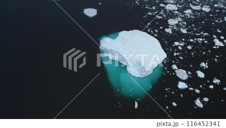 Massive snow covered iceberg with blue ice melting underwater floats in Antarctic ocean. Antarctica icy landscape. Polar ecology, melting ice, climate change, global warming. Aerial drone zoom in shot 116452341