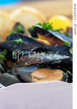 A paper container filled with mussels and bread is placed on the table A paper container filled with mussels and bread is placed on the table 116452649
