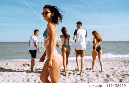 Group of friends having fun and running along beach. Young friends enjoying on beach holiday. Summertime 116452929