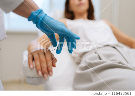 Closeup of unrecognizable doctor acupuncturist in latex gloves inserting needle into arm of female patient during acupuncture therapy. Young woman receiving arm acupuncture at clinic, selective focus. Closeup of unrecognizable doctor acupuncturist in latex gloves inserting needle into arm of female patient during acupuncture therapy. Young woman receiving arm acupuncture at clinic, selective focus. 116453561