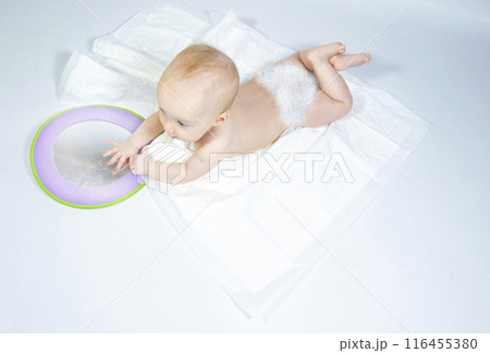 a baby with a mirror lies on a white background 116455380