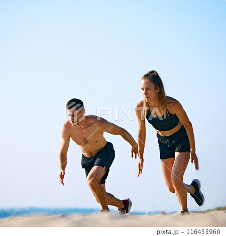Dynamic and hard training outdoor session. Sportive young man and woman training on sandy beach, running under clear sky. 116455960