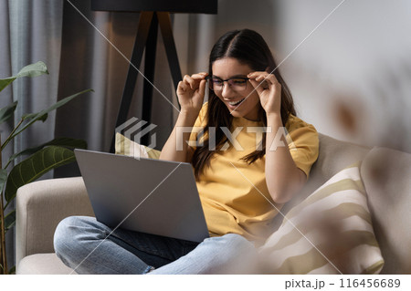Kicking off the new school year right. A young woman vibes out in her cozy spot, diving into homework on her laptop Kicking off the new school year right. A young woman vibes out in her cozy spot, diving into homework on her laptop 116456689