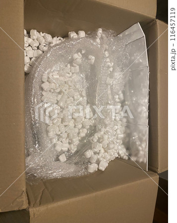 Cardboard box being filled with packing peanuts 116457119