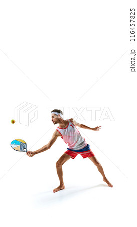 Young focused man, beach tennis player with colorful racket, playing isolated on white background 116457825