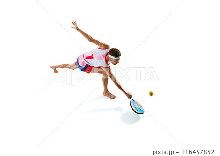 Top view. Dynamic image of sportive young man in colorful uniform in motion, playing beach tennis isolated on white background 116457852