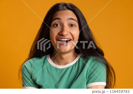 Portrait of emotional young girl in green t-shirt expressing positive shock and excitement against yellow studio background Portrait of emotional young girl in green t-shirt expressing positive shock and excitement against yellow studio background 116459783