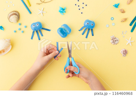 Adorable jellyfish made from plastic blue egg, Kids craft at home or kindergarten. Hands making DIY Adorable jellyfish made from plastic blue egg, Kids craft at home or kindergarten. Hands making DIY 116460968