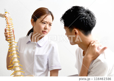骨の模型を使い男性患者に説明する女性医師 116461586