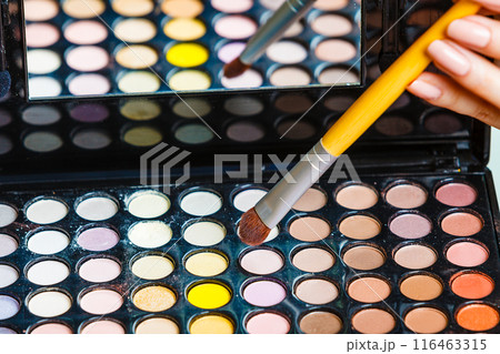Woman holds makeup eye shadows palette and brush. 116463315