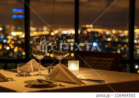 Elegant dining setup with glasses, candlelight and a cityscape at dusk Elegant dining setup with glasses, candlelight and a cityscape at dusk 116464302