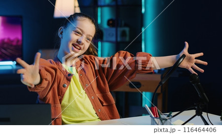 Smiling child filming video for her newly opened online channel, talking with viewers. Gen Z internet star telling audience her name and what topics she wishes to explore in future clips 116464406