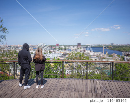 【ウクライナ】首都キーウの旧市街ポジールを見渡せるウッドデッキの展望台で快晴の景色を眺めるカップル 116465165