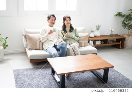テレビや動画などを見るリビングでくつろぐ50代の夫婦の全身　話す会話するカップルの正面の全身 116466332