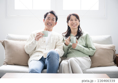 テレビや動画などを見るリビングでくつろぐ50代の夫婦の全身　話す会話するカップルの正面の全身 116466339