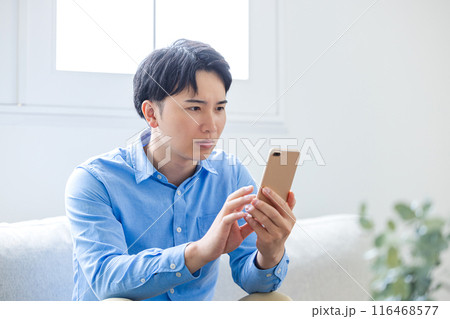 真剣な眼差しでスマホを見る青年 真剣な眼差しでスマホを見る青年 116468577