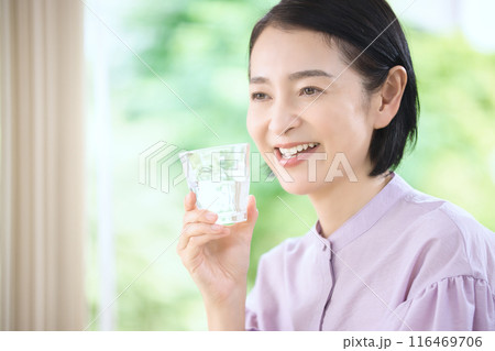 リビングで水を飲む笑顔のミドル女性 116469706