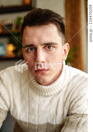 Man in White Sweater Looking at Camera 116470204