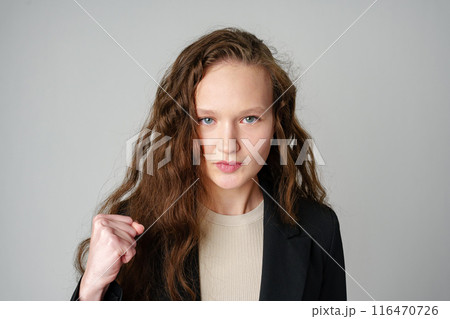 Young Woman in Casual Attire Smiling and Making a Fist Pump Gesture on a Plain Background Young Woman in Casual Attire Smiling and Making a Fist Pump Gesture on a Plain Background 116470726