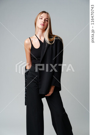 Young Woman Model in Black Top and Pants Posing on gray background Young Woman Model in Black Top and Pants Posing on gray background 116470743