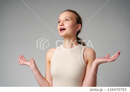 Startled Woman With Surprised Expression on gray background 116470783