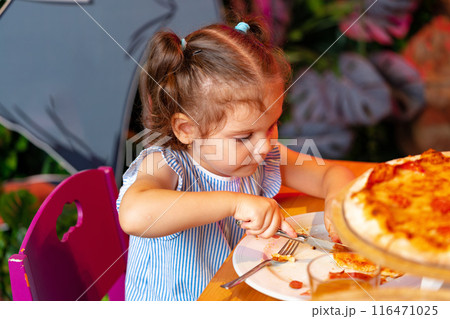 Young Girl Enjoying a Slice of Pizza at a Birthday Party Indoors 116471025