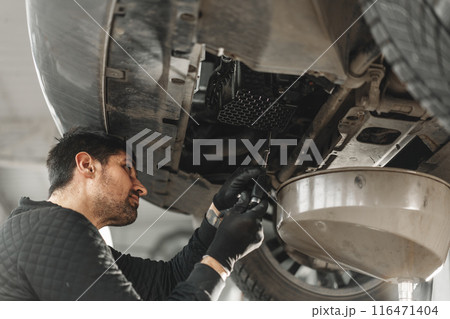 Car mechanic changing oil in a car service 116471404