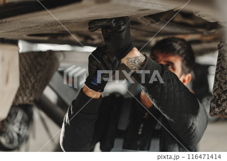 Workman mechanic working under car in auto repair shop Workman mechanic working under car in auto repair shop 116471414