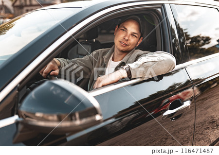 Young smiling man sitting in a car with open window 116471487