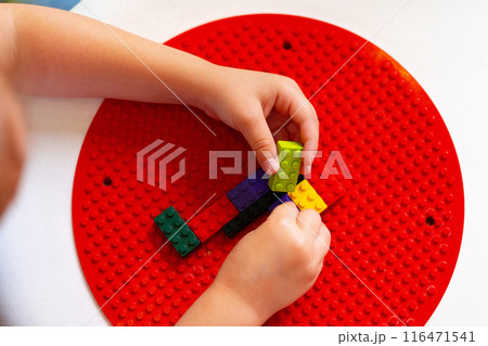 Child Engaged in Creative Play With Colorful Building Blocks on a Round Base 116471541