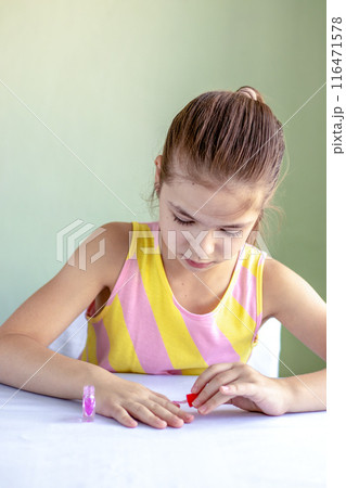 Adorable little girl painting her nails with pink polish 116471578