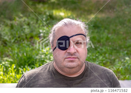 Close-up portrait of a blind, visually impaired man with a black medical patch on his eye 116471582