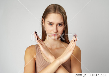 Young serious woman crossed hands show stop symbol on gray background Young serious woman crossed hands show stop symbol on gray background 116471587